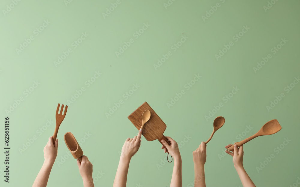 Wall mural women with wooden kitchen utensils on green background