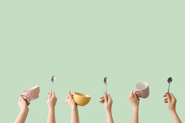 Women with mugs and spoons on green background