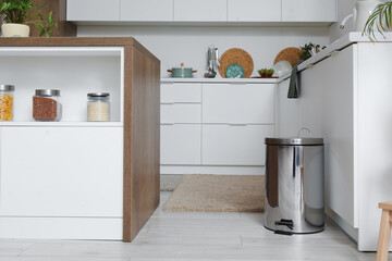 Metallic trash bin in interior of light kitchen