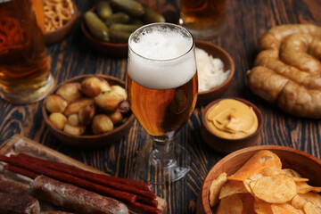 Glass of cold beer and different snacks on wooden background. Oktoberfest celebration - obrazy, fototapety, plakaty