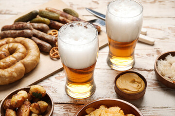 Glasses of cold beer and different snacks on light wooden background. Oktoberfest celebration