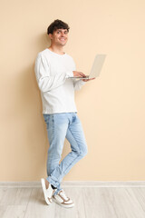 Male programmer working with laptop near beige wall