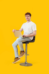 Male programmer working with laptop on yellow background