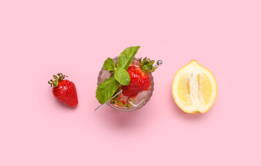 Glass of fresh lemonade with strawberry and lemon on pink background