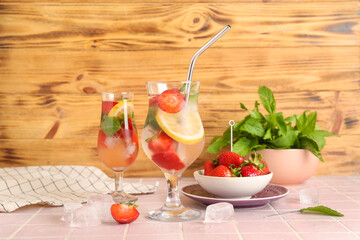 Glasses of fresh lemonade with strawberry and lemon on pink tile table
