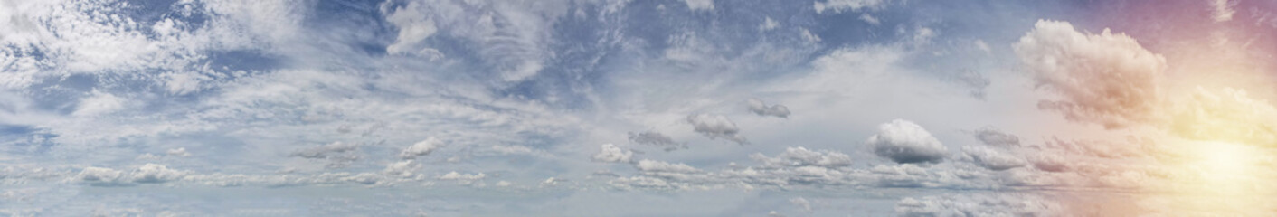 Panorama landscape of serene sky adorned with beautiful white clouds while the gentle touch of the sun light on the right side.