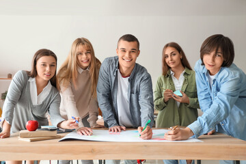 Group of teenage students performing task at table in classroom