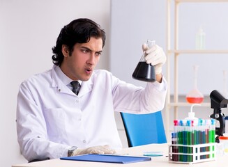 Young handsome chemist working in the lab