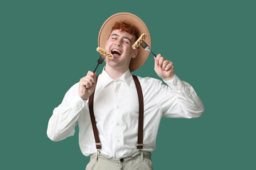 Young man in traditional German clothes with sausages on green background