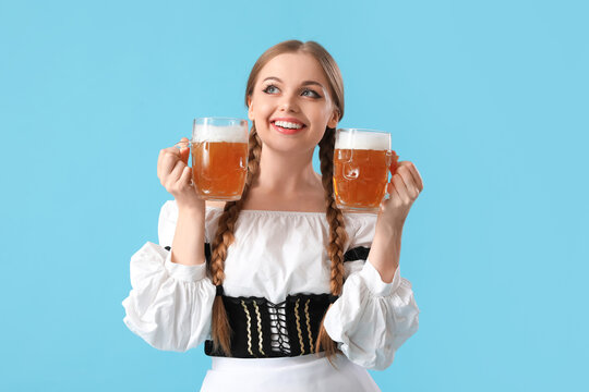 Beautiful Octoberfest waitress with beer on blue background