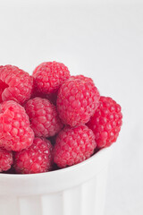 Bowl with fresh organic raspberry close up on a white background. Copy space.