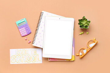Card with text BACK TO SCHOOL, tablet and stationery on brown background