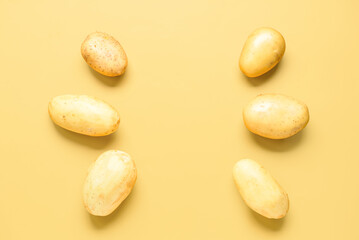 Raw potatoes on yellow background