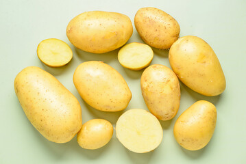 Raw potatoes on green background