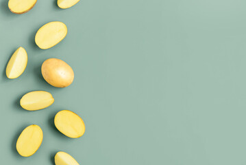 Raw potatoes on green background