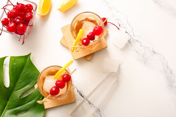 Glasses of tasty cocktail with maraschino cherries on white marble background
