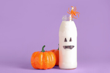 Bottle of milk and pumpkins for Halloween on purple background