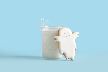 Glass of milk and tasty cookie for Halloween on blue background