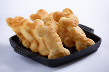 Porcão de pastéis em formato de ossos para cachorro em uma cumbuca preta, em um fundo branco