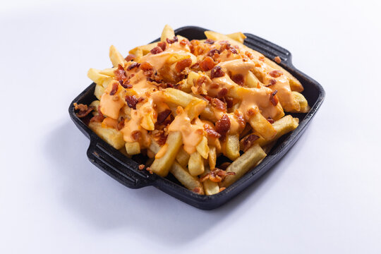 Batata frita com queijo cheddar e bacon, servida em uma cumbuca preta em um fundo branco