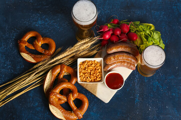 Glasses of cold beer and different snacks on blue background. Oktoberfest celebration