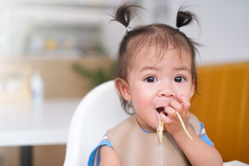 Little cute girl eating spaghetti pasta. baby girl sit in the white kitchen. baby playing food....