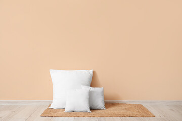 Fototapeta na wymiar White pillows on wicker mat near beige wall