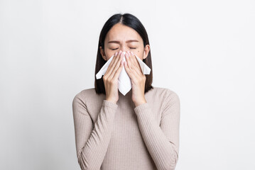Portrait of beautiful young asian sick woman over center of isolated white background being wrapped in scarf sneezing, suffering from runny nose and high temperature. Cold and fever concept.
