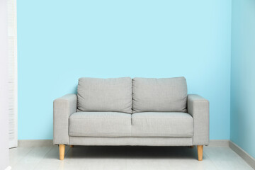 Cozy grey sofa near blue wall