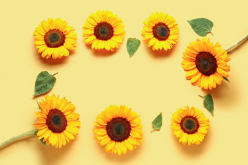 Frame made of beautiful sunflowers and leaves on yellow background