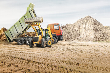 Obraz premium Modern construction machinery at a construction site in a quarry. Powerful modern equipment for earthworks. Rental of construction equipment. Excavator, dump truck, bulldozer, loader.