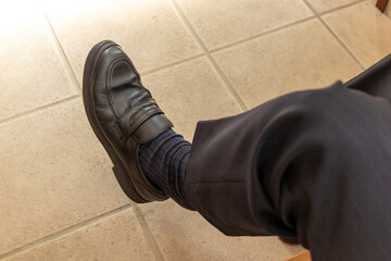 黒のビジネスシューズを履いた男性の足
