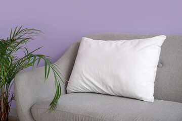 Grey sofa with white pillow near lilac wall