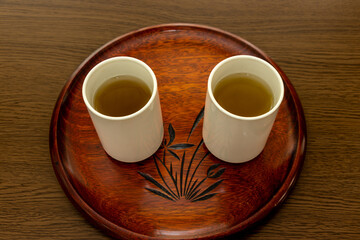 丸いお盆の上にお茶の入った二つのコップ	
