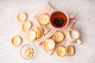 Homemade tartlets and cup of hot tea on light background