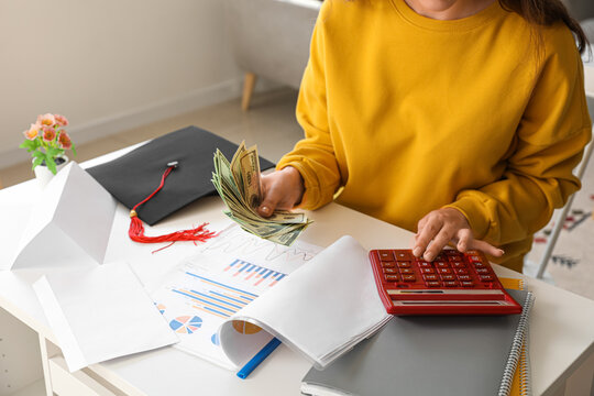 Female Student Calculating Finances And Holding Dollar Banknotes. Student Loan Concept