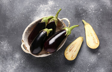 Wicker basket with fresh eggplants on grey background