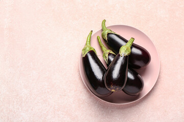 Plate with fresh eggplants on beige background