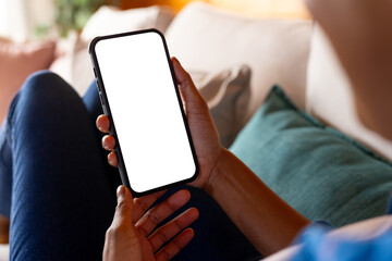 African american woman relaxing on sofa using smartphone with copy space on screen at home