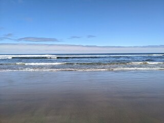 Towards the ocean with waves breaking on the beach on the clear day. 