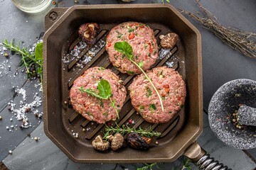 Gourmet Creation: Top View of Raw Hamburger Patties with Spices Sizzling in a Cast Iron Pan, Awaiting Culinary Perfection in 4K Resolution