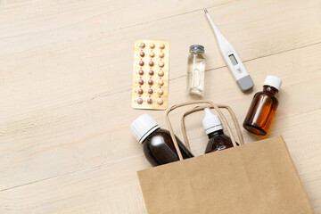 Shopping bag with different medicines on wooden background