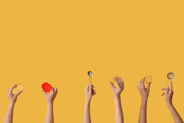 Female hands with baking utensils on yellow background