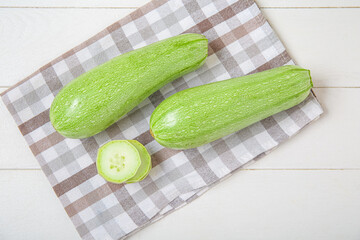 Fresh green zucchini on white wooden background