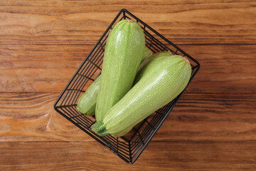 Basket with fresh green zucchini on wooden background