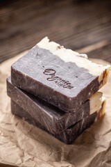 Pieces of natural handmade chocolate soap on a kraft paper wrapper on a wooden table