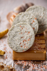 Natural soap with sea salt on a wooden soap dish, shells and a starfish. Organic summer soap, immersing in the marine atmosphere