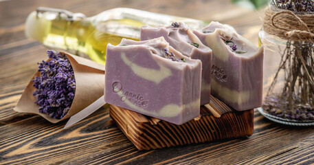 Obraz na płótnie Canvas Pieces of traditional French soap on a wooden soap dish and a bouquet of lavender. Natural handmade Marseille soap with lavender fragrance