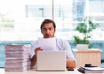 Young male employee unhappy with excessive work in the office