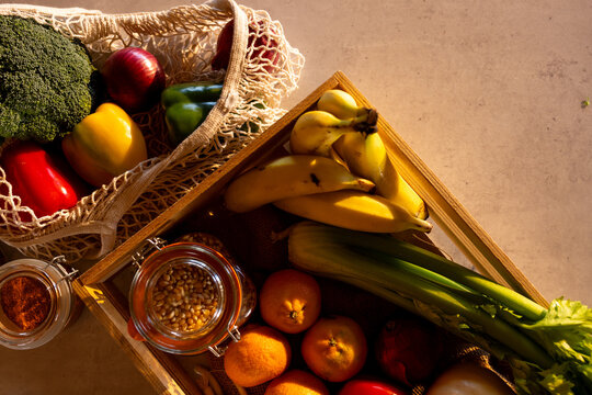 Fresh vegetables, fruit and grains in crate and re-usable shopping bag on counter in sunny kitchen